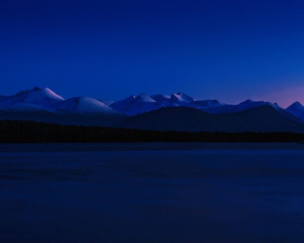 Night photograph of some blue mountains with purple peaks