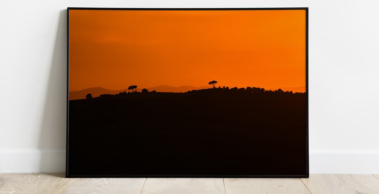 Mockup of a wall art showing a sunset and the silhouette of a hill and some trees.