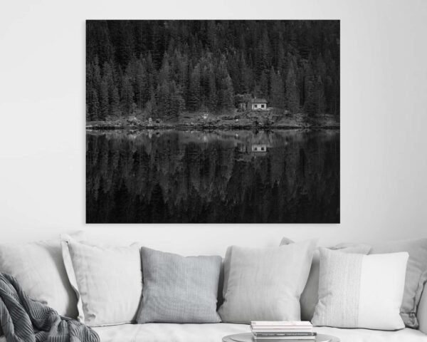 Black and white photograph of a house and a forest hanging above a sofa